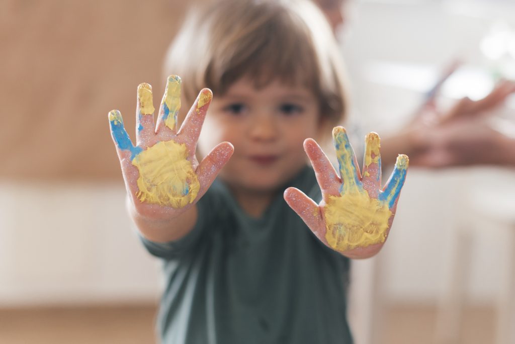 Menino com as mãos pintadas e acessibilidade